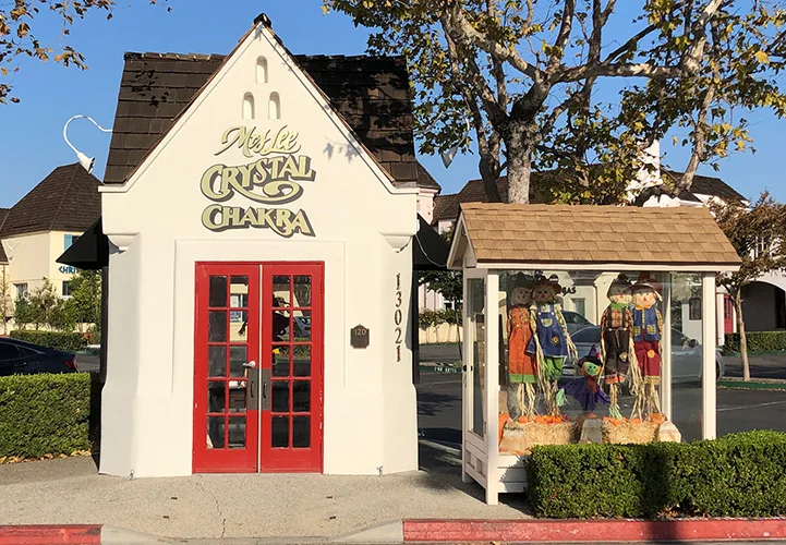 A photo of Mrs. Lee's Crystal Chakra studio and place of business. A small white building with red french doors and a steep sloped roof.
