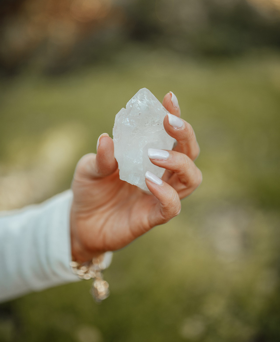 A womans hand is seen holding a large chunk of white quartz.